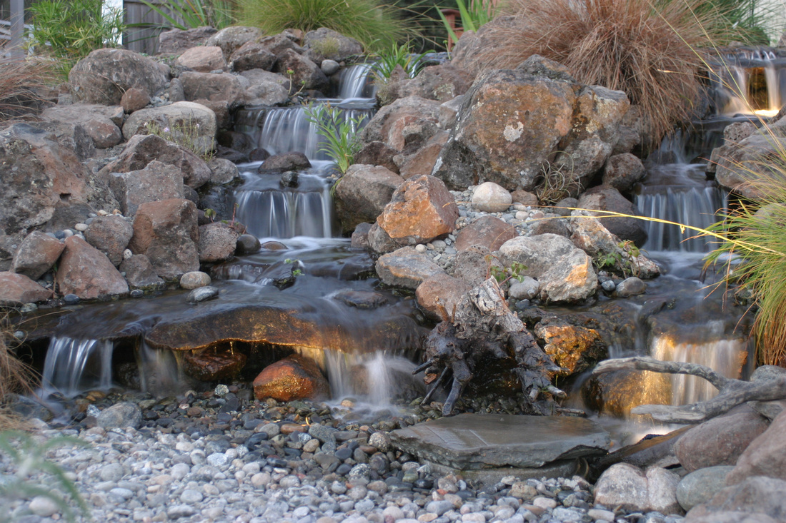 Disappearing or pondless waterfall with multiple tiers and rock bed
